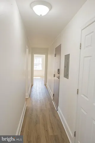 a view of a hallway with wooden floor and a bathroom