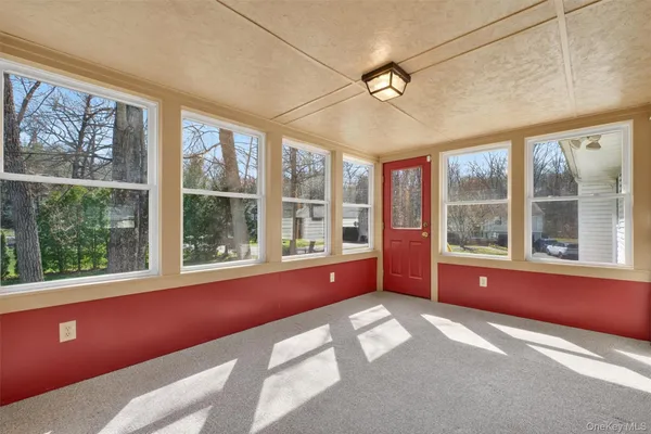 a view of an empty room with a window and chandelier fan