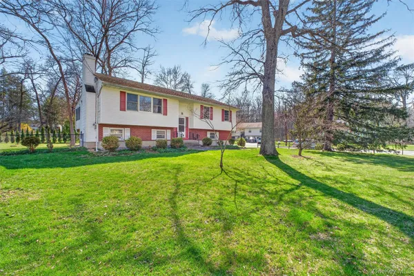 a view of a house with a big yard and large trees