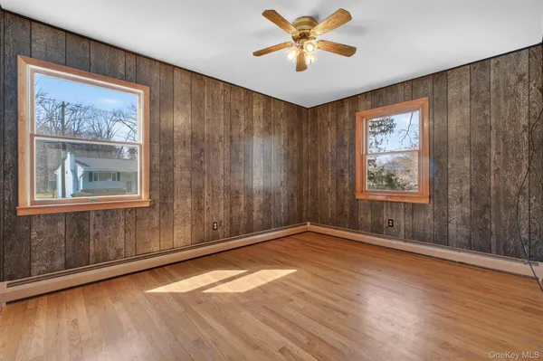 a view of an empty room with a window and wooden floor