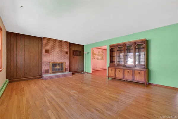 a view of an empty room with window and wooden floor