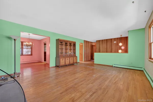 a view of an empty room with window and wooden floor