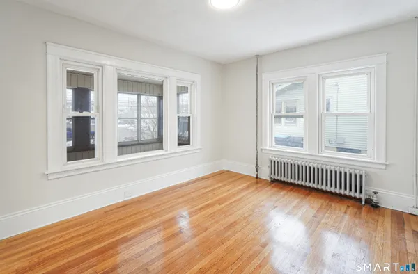 a view of an empty room with wooden floor and a window