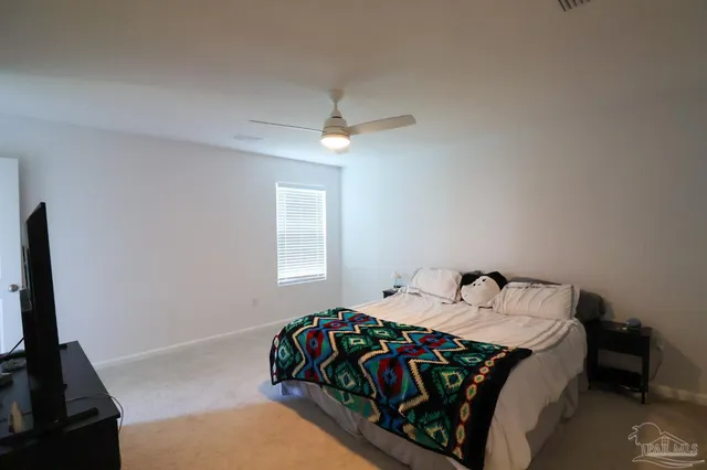 a bedroom with a bed and a flat tv screen on the dresser