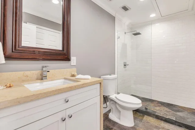 a bathroom with a granite countertop toilet a sink a mirror and a shower