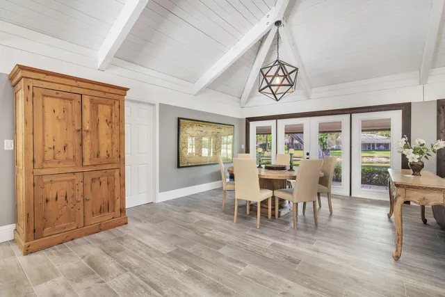 a dining room with wooden floor a chandelier a wooden table and chairs