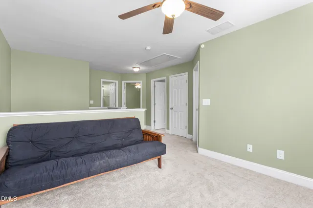 a living room with couches and ceiling fan