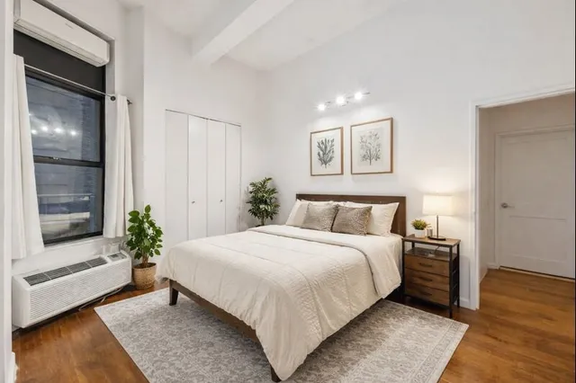 a bedroom with a large bed and a potted plant