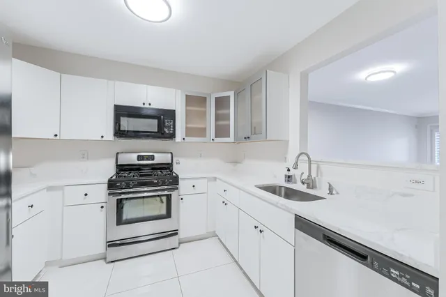 a kitchen with white cabinets appliances and a sink