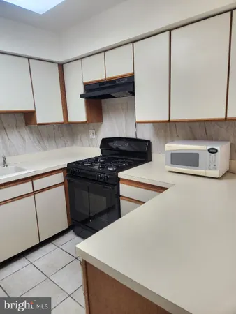 a kitchen with stainless steel appliances a stove a sink and white cabinets