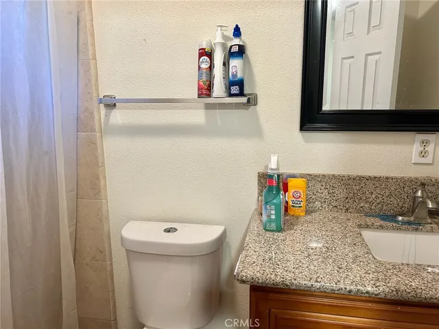 a bathroom with a granite countertop sink and a toilet