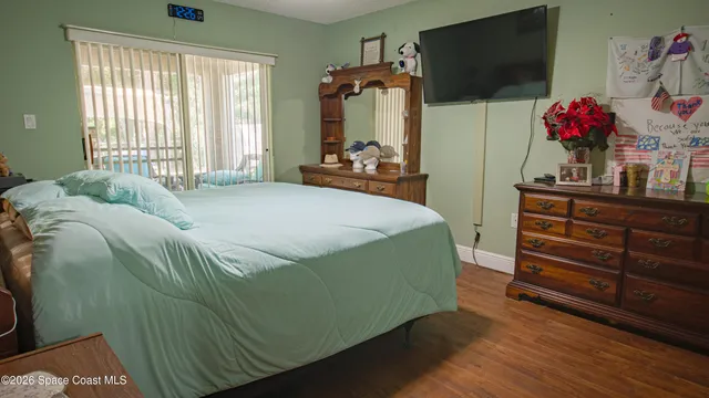a bedroom with a bed and a flat tv screen on dresser