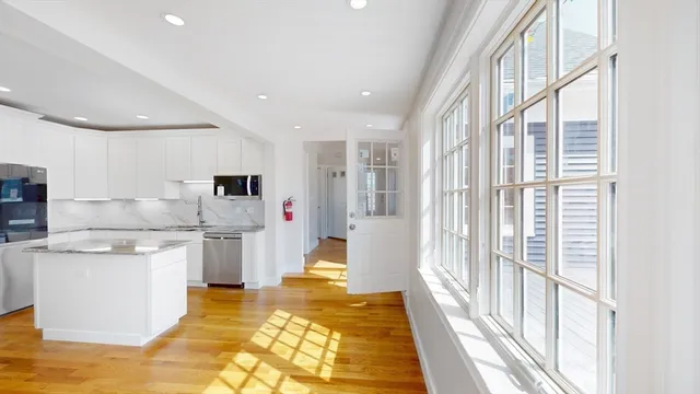 a view of a kitchen with kitchen island a stove a refrigerator wooden floor and a view of living room