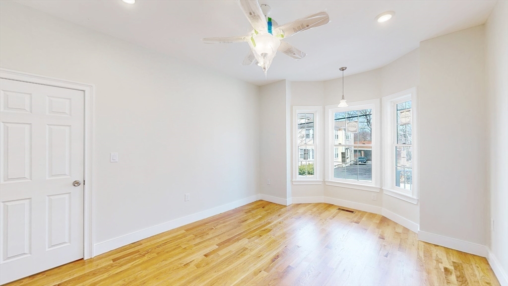 48 Rockwell Street, Unit 1 Malden, MA 02148 - Photo 10 of 34 an empty room with wooden floor chandelier fan and windows