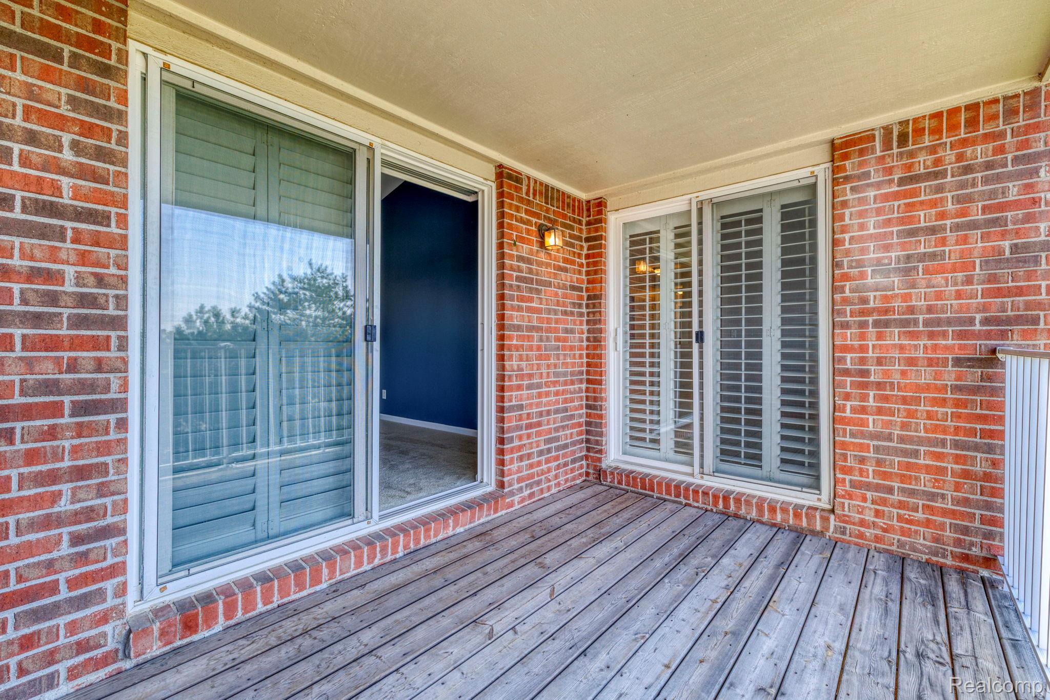 1905 Flagstone Circle Rochester, MI 48307 - Photo 30 of 33 Private balcony featuring wood-finish decking, brick exterior walls, an outdoor wall sconce, and sliding glass doors with louvered shutters