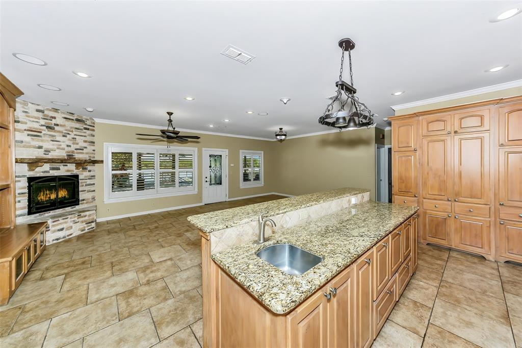 566 Selma Park Road Bowie, TX 76230 - Photo 11 of 40 Spacious kitchen with wood cabinetry and light granite countertops, featuring a kitchen island with an undermount sink and a breakfast bar