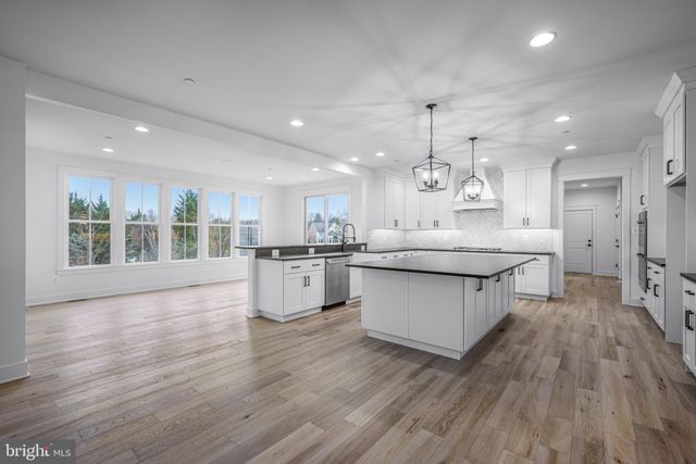a large white kitchen with lots of counter space a sink appliances and cabinets
