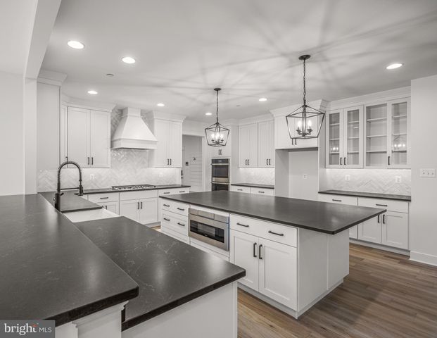 a kitchen with stainless steel appliances granite countertop a sink a stove and a wooden floors