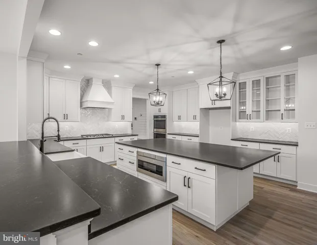 a kitchen with stainless steel appliances granite countertop a sink a stove and a wooden floors