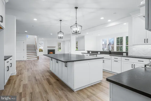 a kitchen with granite countertop a sink dishwasher a stove and a wooden floor