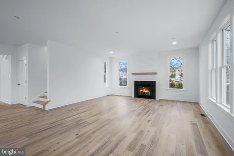 an empty room with wooden floor fireplace and windows