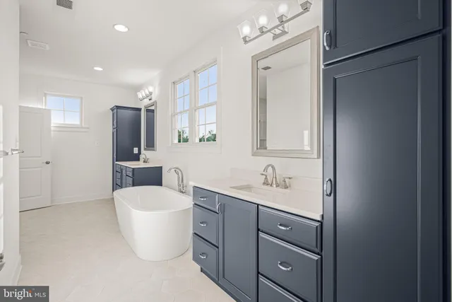 a spacious bathroom with a double vanity sink a large mirror and a bathtub