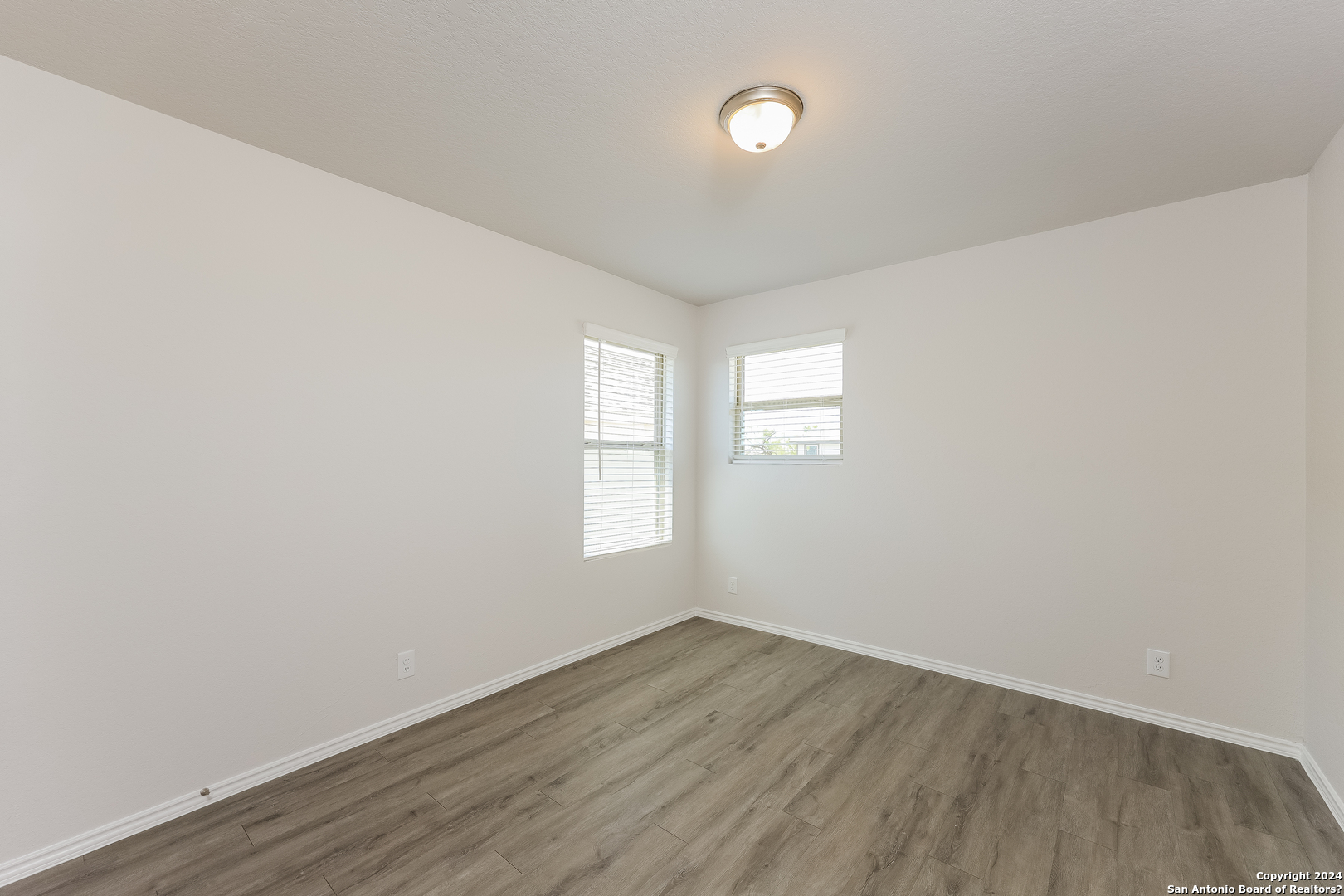 10702 Apple Pie Road San Antonio, TX 78224 - Photo 12 of 19 an empty room with wooden floor and windows