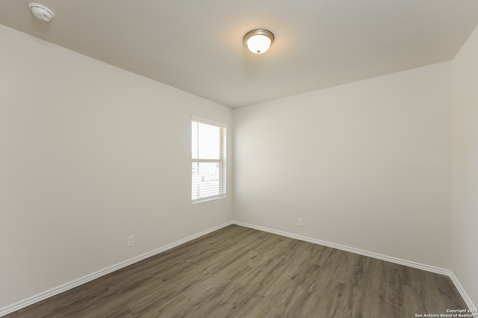 10702 Apple Pie Road San Antonio, TX 78224 - Photo 13 of 19 an empty room with wooden floor and windows