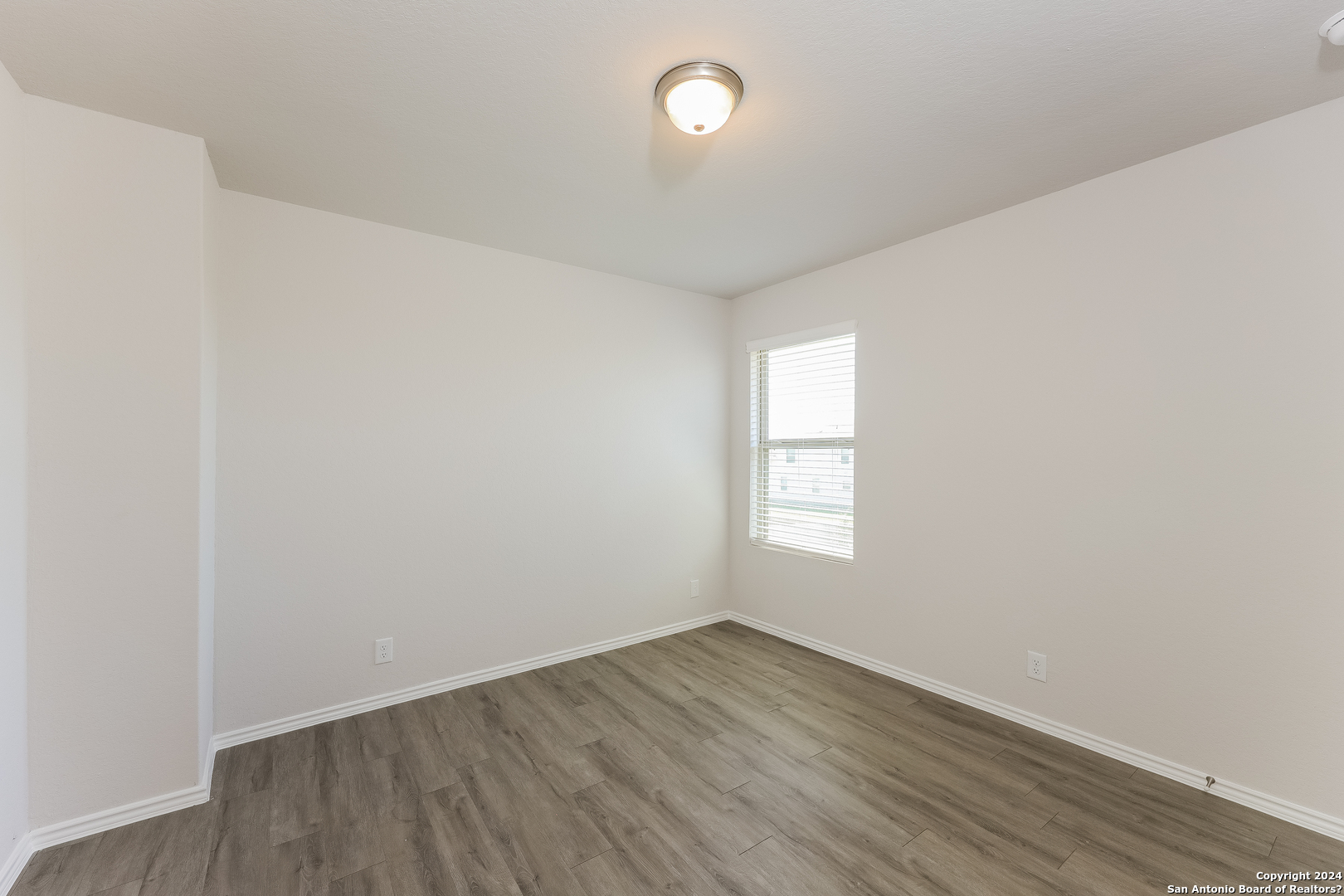 10702 Apple Pie Road San Antonio, TX 78224 - Photo 14 of 19 an empty room with wooden floor and windows