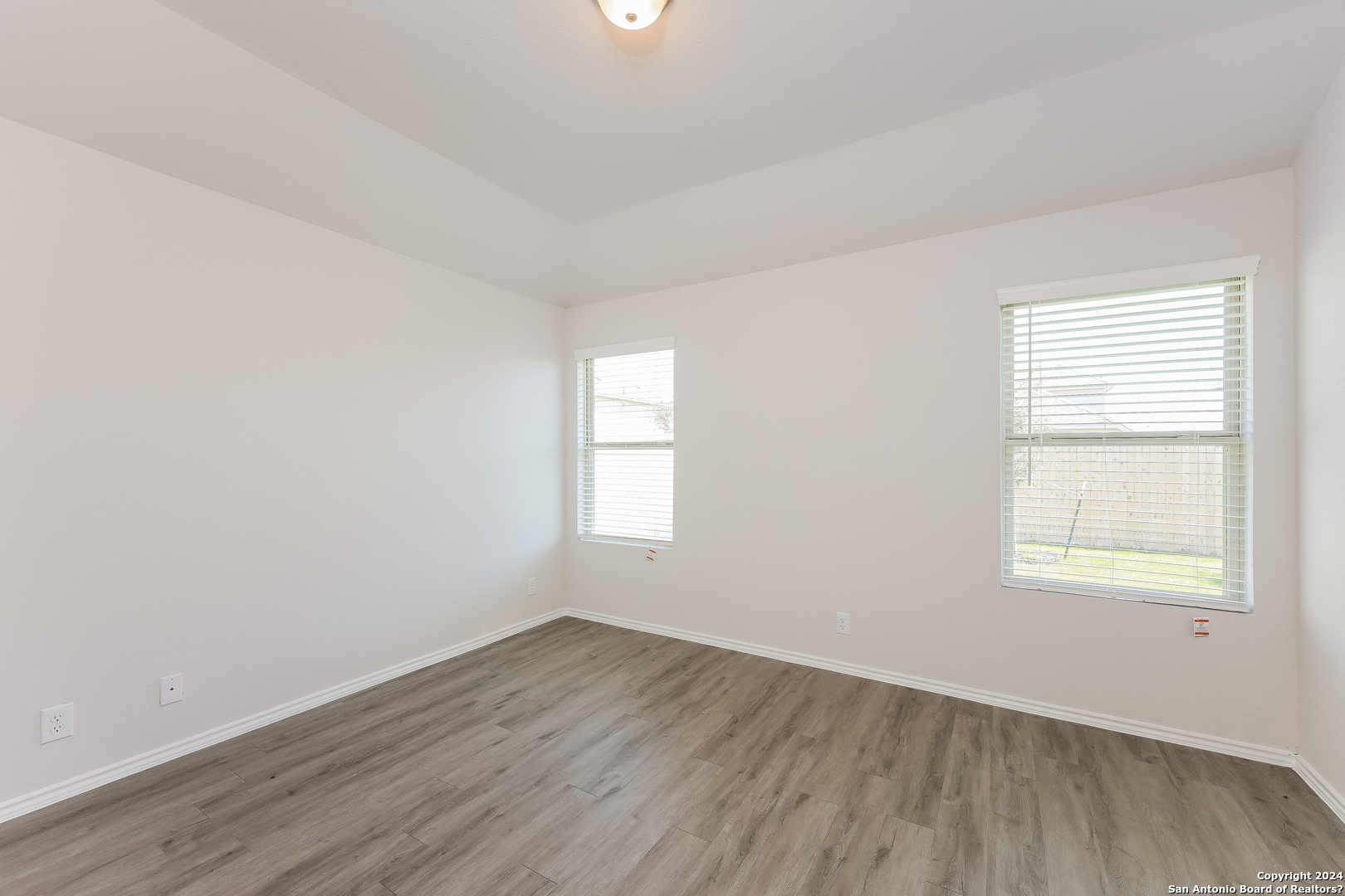 10702 Apple Pie Road San Antonio, TX 78224 - Photo 10 of 19 an empty room with wooden floor and windows
