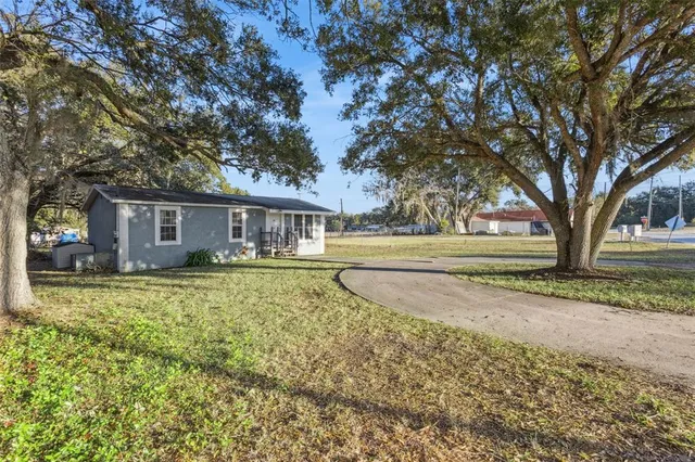 a view of a house with a big yard and large trees