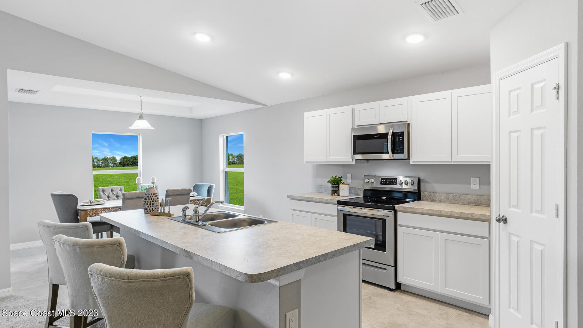 1365 Ran Road Southeast Palm Bay, FL 32909 - Photo 5 of 15 a kitchen with stainless steel appliances a stove a sink a microwave a refrigerator white cabinets and couches