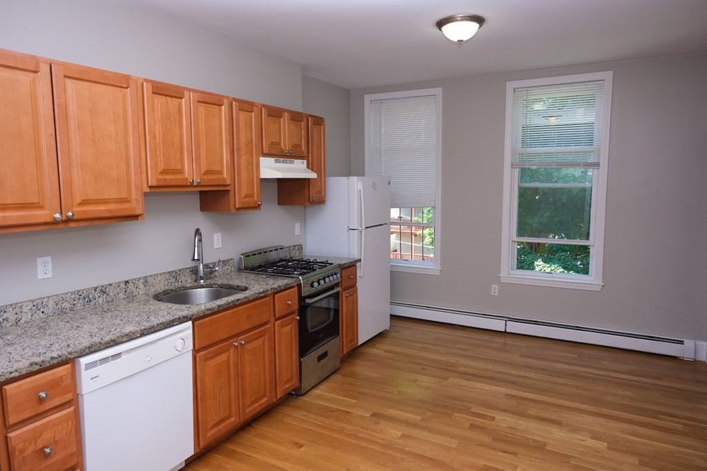a kitchen with granite countertop wooden cabinets stainless steel appliances and a window
