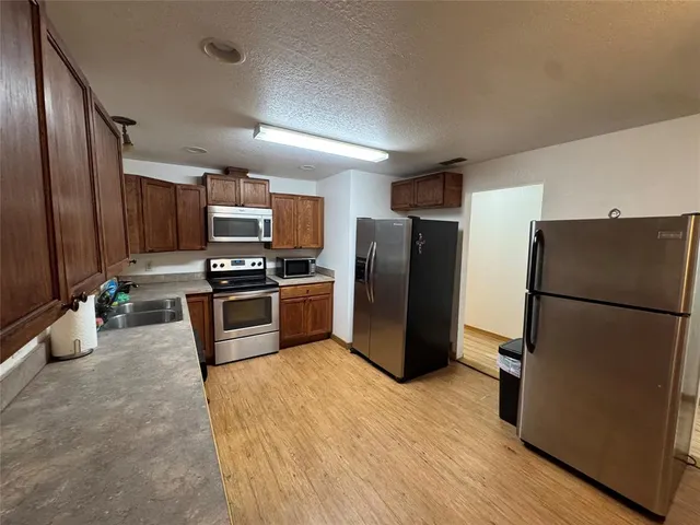 a kitchen with a refrigerator sink and wooden cabinets