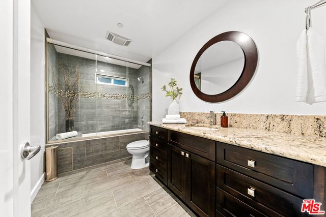 a bathroom with a granite countertop toilet a sink and a mirror