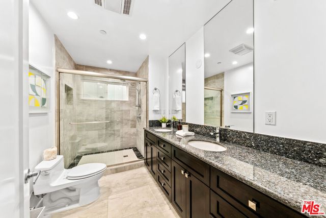 a bathroom with a granite countertop sink toilet a large mirror a shower and vanity