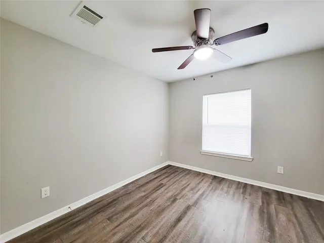 an empty room with a window and a ceiling fan