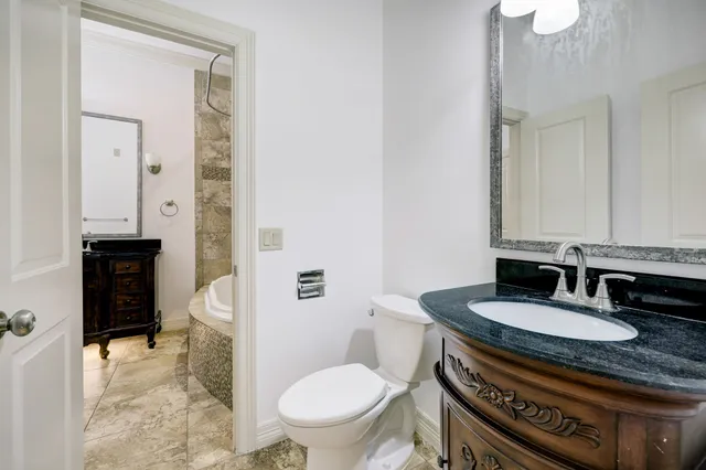a bathroom with a granite countertop toilet a sink and a mirror