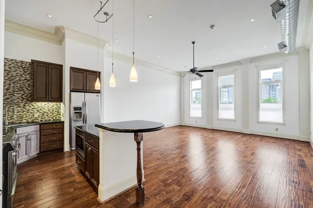 a kitchen with stainless steel appliances kitchen island a hardwood floor and a view of living room