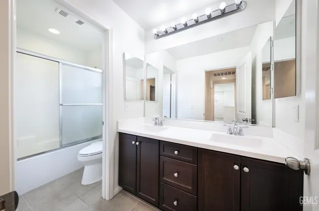 a bathroom with a double vanity sink toilet and shower