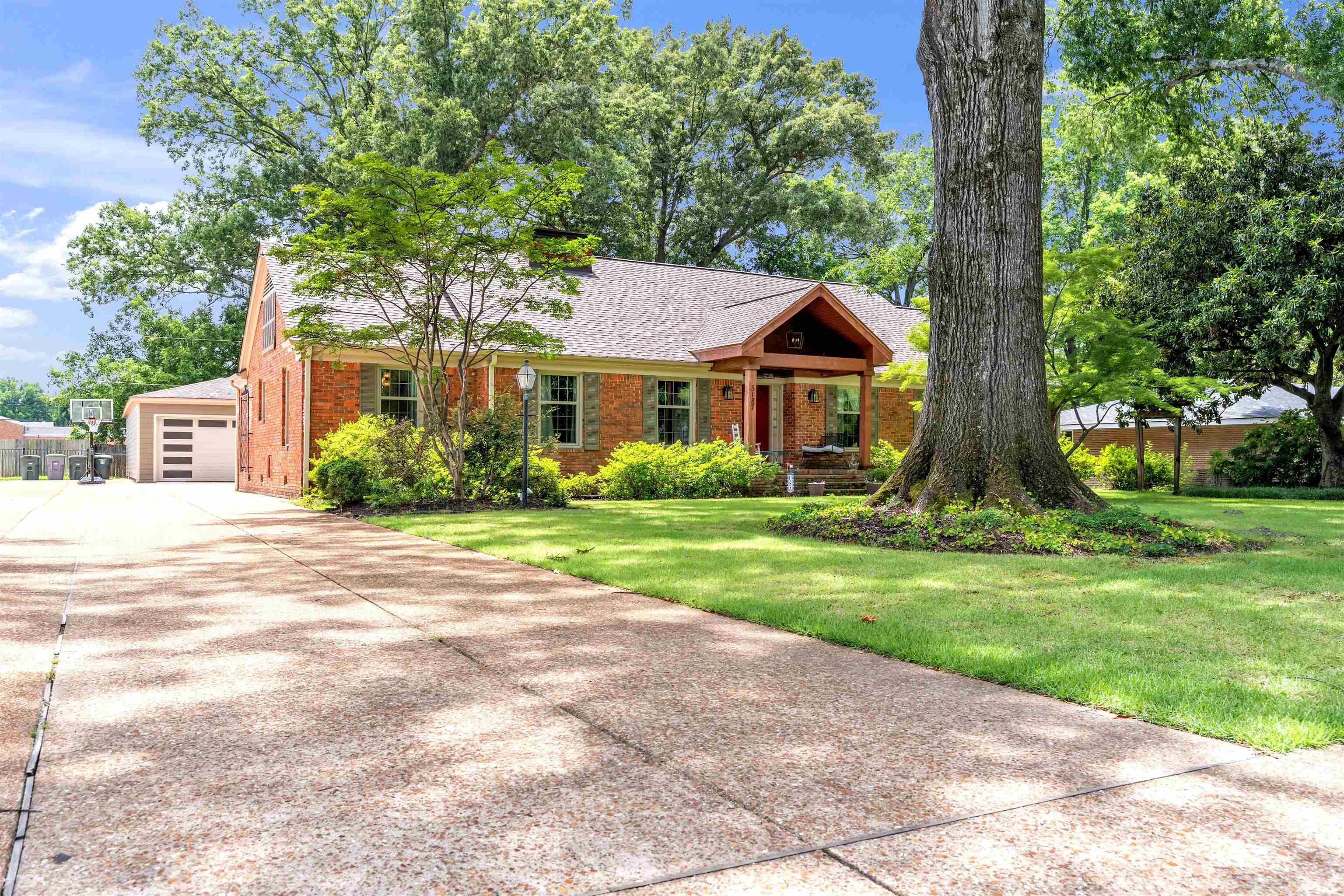 5187 South Angela Road Memphis, TN 38117 - Photo 2 of 39 Brick exterior residence featuring a covered front entry, traditional shutters, and a prominent mature tree