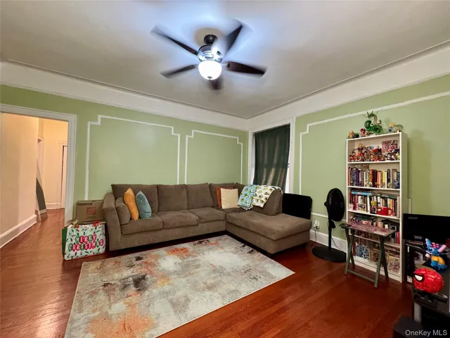 a living room with furniture and a bookshelf with wooden floor