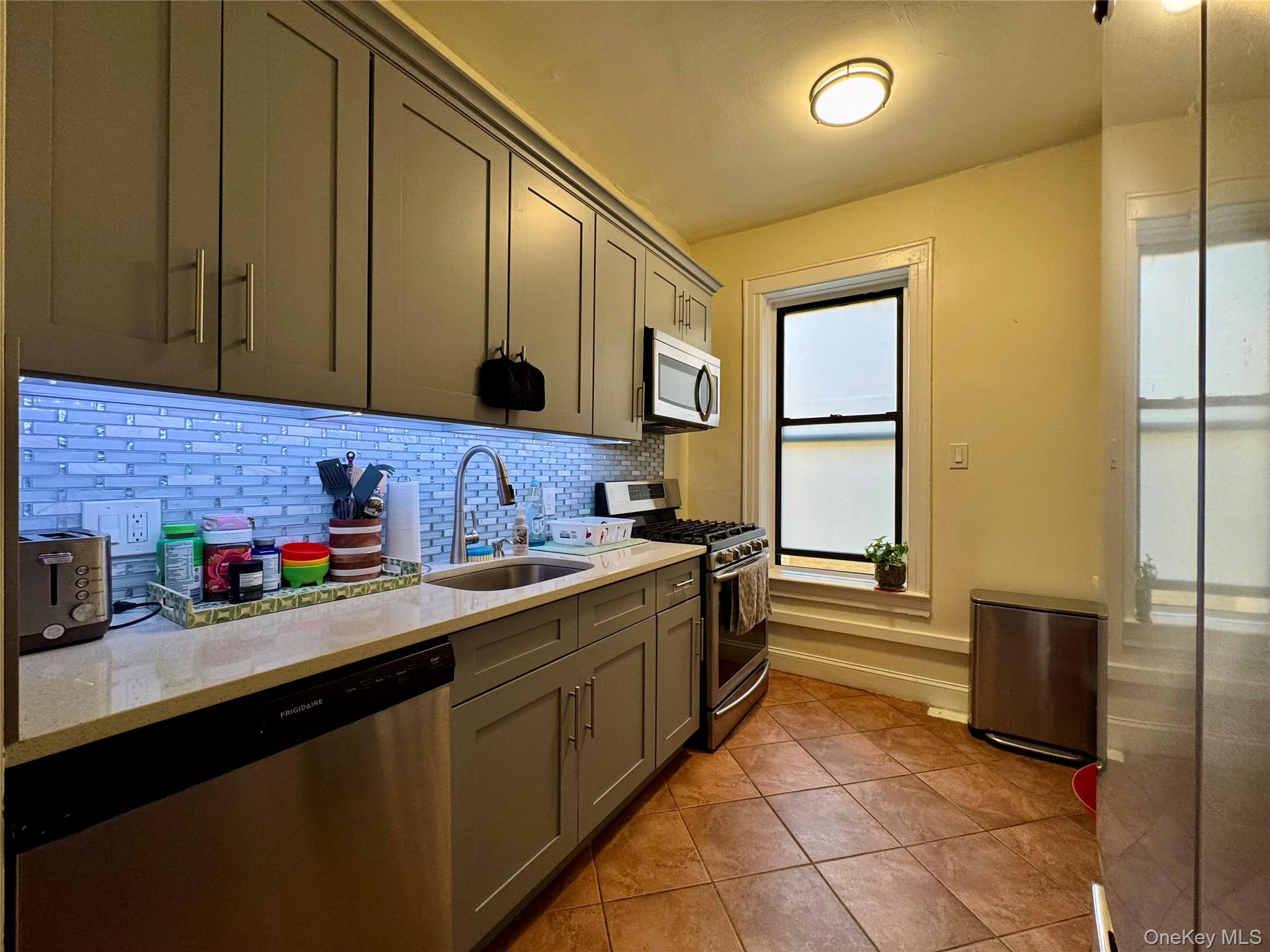 83-64 Talbot Street, Unit 3A Queens, NY 11415 - Photo 10 of 19 a kitchen with stainless steel appliances a sink stove and cabinets