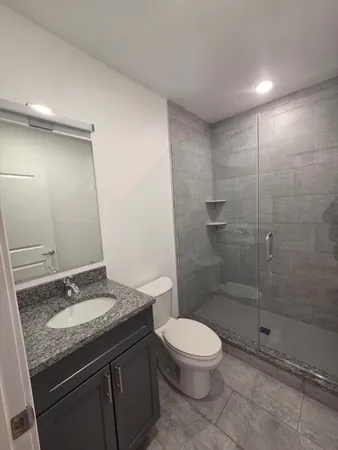 a bathroom with a granite countertop sink a toilet and shower