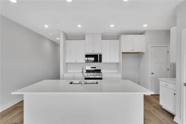 a kitchen with stainless steel appliances a stove top oven a refrigerator and white cabinets