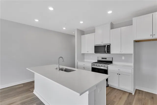a kitchen with granite countertop a sink stainless steel appliances and white cabinets