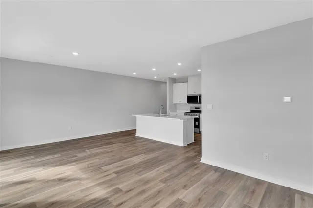 a view of kitchen with kitchen island wooden floor appliances and cabinets