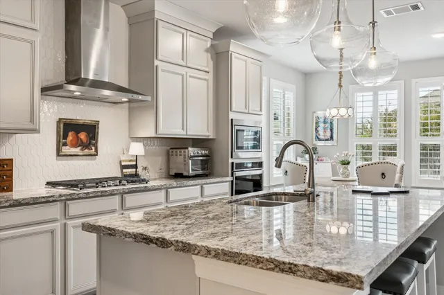 a kitchen with stainless steel appliances granite countertop a sink window and cabinets