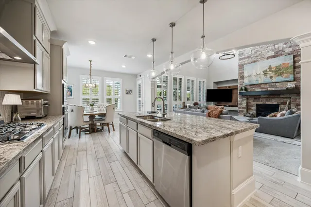 a kitchen with stainless steel appliances granite countertop a stove and a view of living room
