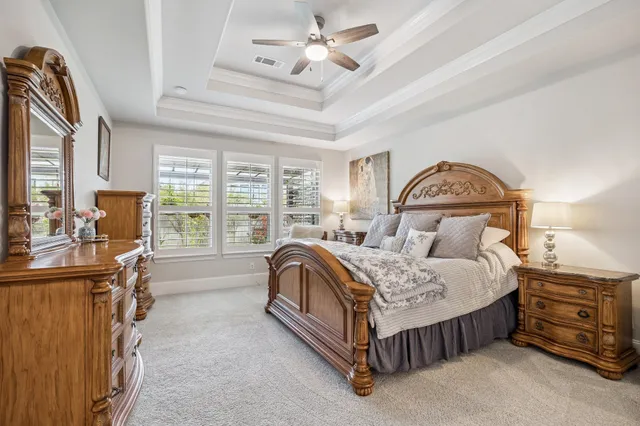 a spacious bedroom with a bed a window and dresser